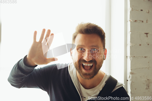 Image of Caucasian musician greeting audience during concert at home isolated and quarantined, smiling, cheerful