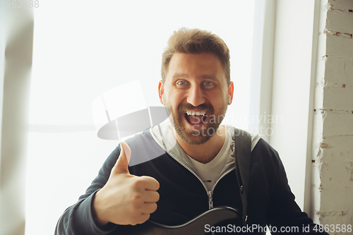 Image of Caucasian musician greeting audience during concert at home isolated and quarantined, smiling, cheerful