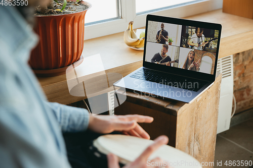 Image of Caucasian musician playing hand drum during concert at home isolated and quarantined, playing with the band in online streaming, conference