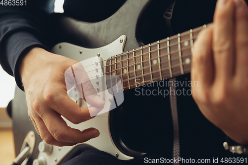 Image of Caucasian musician playing guitar during concert at home isolated and quarantined, cheerful improvising, close up