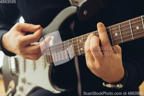 Image of Caucasian musician playing guitar during concert at home isolated and quarantined, cheerful improvising, close up