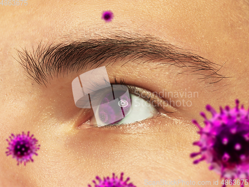 Image of Close up shoot of a male eye with 3D-illustrated coronavirus models, the way of infecting