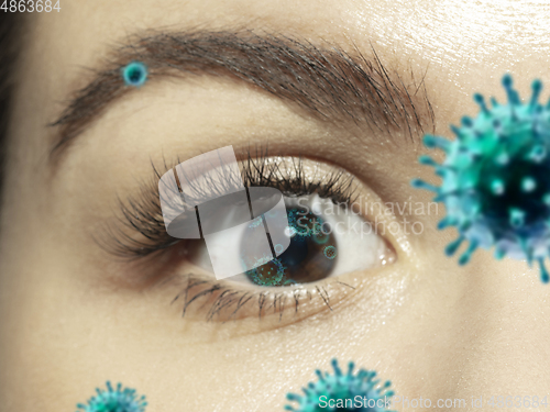 Image of Close up shoot of a female eye with 3D-illustrated coronavirus models, the way of infecting