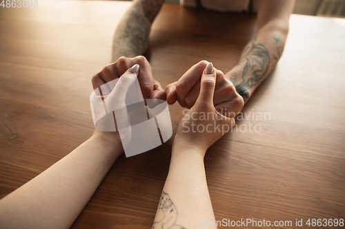 Image of Loving couple holding hands close-up on wooden background, romantic