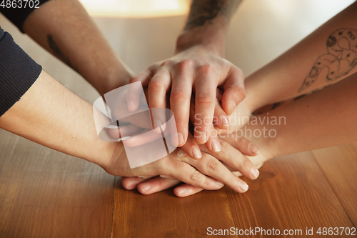 Image of Close up of caucasian male and female hands, covering one another, team, friendship, business