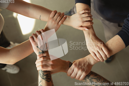 Image of Close up of caucasian male and female hands, covering one another, team, friendship, business