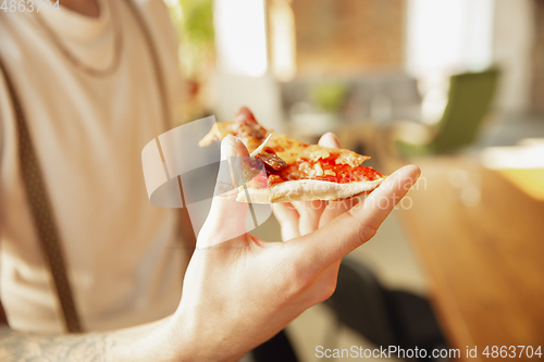 Image of Close up of male hands holding pizza, eating, proposing