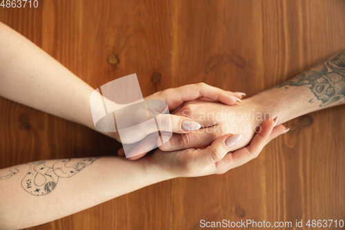 Image of Loving couple holding hands close-up on wooden background, romantic