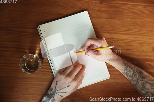 Image of Close up of male hands writing on an empty paper, education and business concept, top view