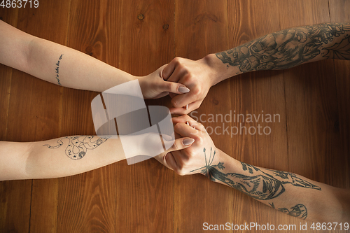 Image of Loving couple holding hands close-up on wooden background, romantic