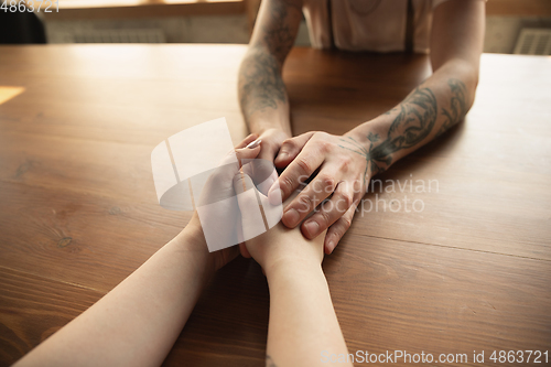 Image of Loving couple holding hands close-up on wooden background, romantic