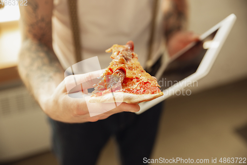 Image of Close up of male hands holding pizza and tablet, proposing