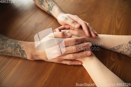 Image of Loving couple holding hands close-up on wooden background, romantic