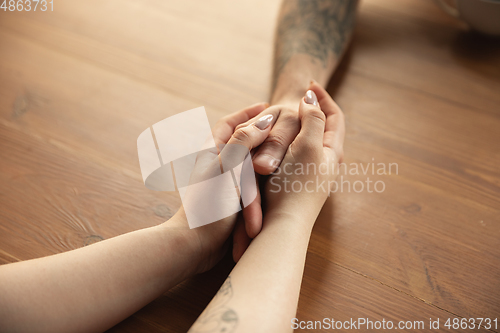 Image of Loving couple holding hands close-up on wooden background, romantic