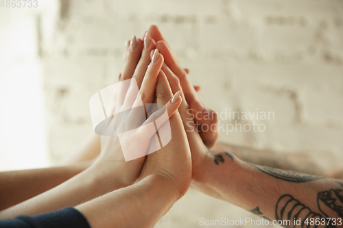 Image of Close up of caucasian male and female hands, covering one another, team, friendship, business