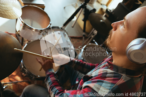 Image of Caucasian musician playing drumms during online concert with the band at home isolated and quarantined, inspired improvising