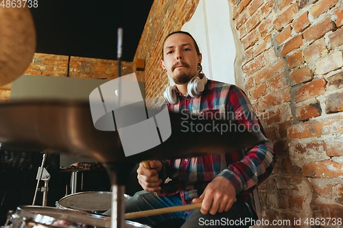 Image of Caucasian musician playing drumms during online concert with the band at home isolated and quarantined, inspired improvising, close up