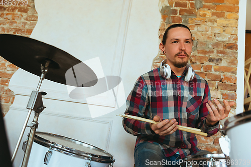 Image of Caucasian musician playing drumms during online concert with the band at home isolated and quarantined, smiling, cheerful