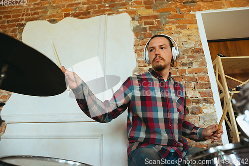 Image of Caucasian musician playing drumms during online concert with the band at home isolated and quarantined, inspired improvising