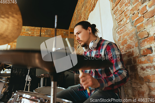 Image of Caucasian musician playing drumms during online concert with the band at home isolated and quarantined, inspired improvising, close up