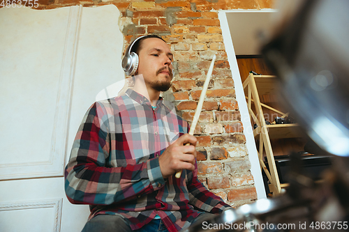 Image of Caucasian musician playing drumms during online concert with the band at home isolated and quarantined, inspired improvising