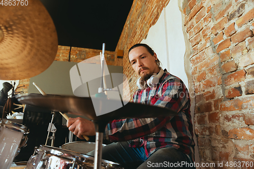 Image of Caucasian musician playing drumms during online concert with the band at home isolated and quarantined, inspired improvising, close up