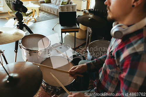 Image of Caucasian musician playing drumms during online concert with the band at home isolated and quarantined, inspired improvising, close up