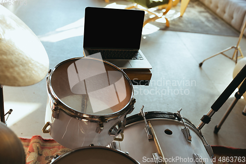 Image of Caucasian musician playing drumms during online concert with the band at home isolated and quarantined, focus on blank laptop screen