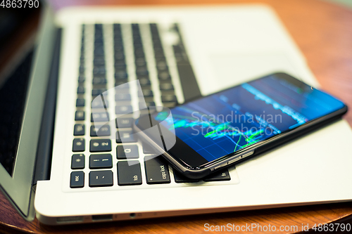 Image of Laptop computer and cellphone with Stock market chart 
