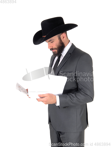 Image of Man in suit and hat reading papers