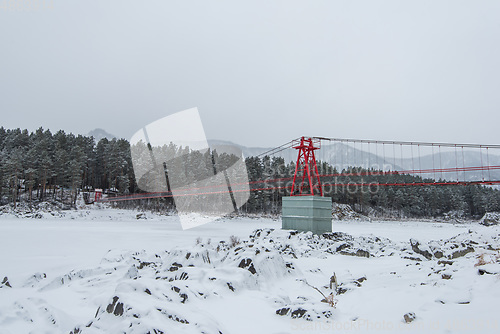 Image of Suspension hanging bridge above winter frozen river