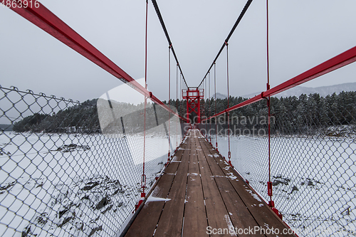 Image of Suspension hanging bridge above winter frozen river