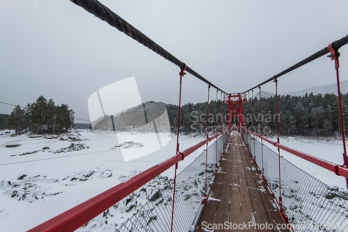 Image of Suspension hanging bridge above winter frozen river
