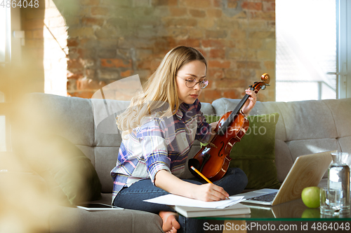 Image of Young woman studying at home during online courses or free information by herself, making notes