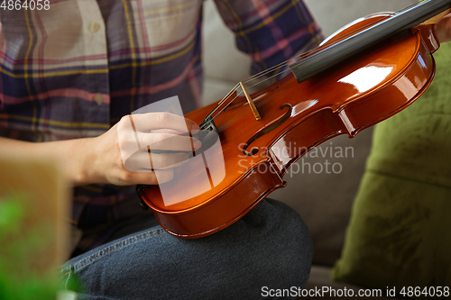 Image of Young woman studying at home during online courses or free information by herself, close up shoot of violin