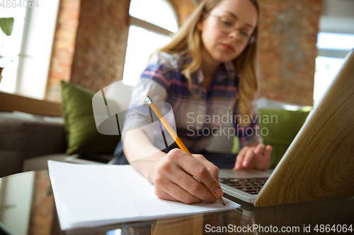 Image of Young woman studying at home during online courses or free information by herself, making notes