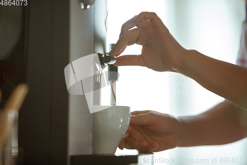 Image of Close up of female hands making coffee on coffee-machine at home or cafe