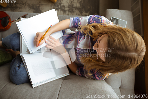 Image of Young woman studying at home during online courses or free information by herself, making notes