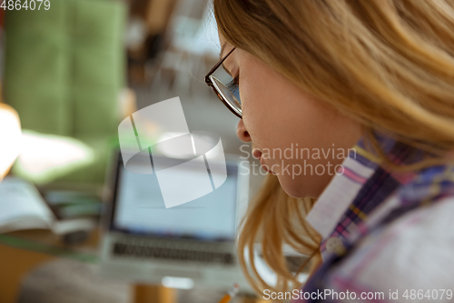 Image of Young woman studying at home during online courses or free information by herself, making notes