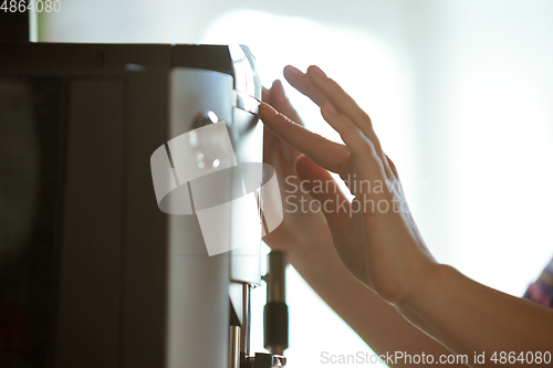 Image of Close up of female hands making coffee on coffee-machine at home or cafe