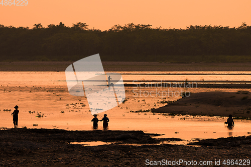 Image of Asian women fishing in the river, silhouette at sunset