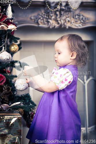 Image of Little girl  is decorating christmas tree