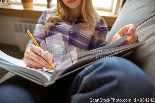 Image of Young woman studying at home during online courses or free information by herself, making notes