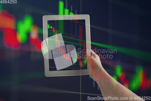 Image of Hands holding tablet showing graphs going down. Double exposure with graphs, digital. Virus alert, coronavirus pandemic, crisis, unemployment