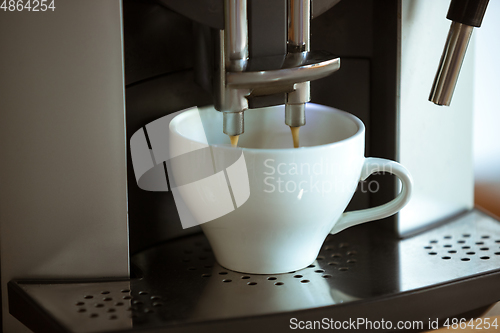 Image of Close up of coffee machine pouring cappuccino, espresso, americano in white cup