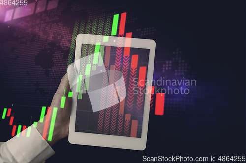 Image of Hands holding tablet showing graphs going down. Double exposure with graphs, digital. Virus alert, coronavirus pandemic, crisis, unemployment