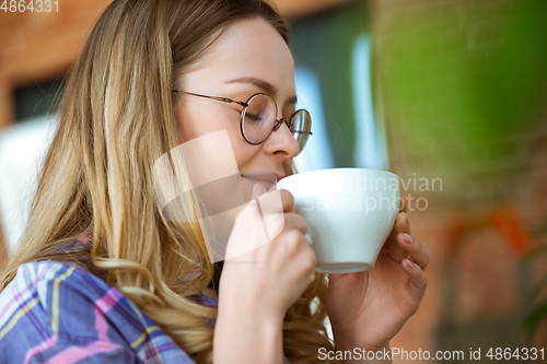 Image of Close up of beautiful joyful woman drinking coffee at home