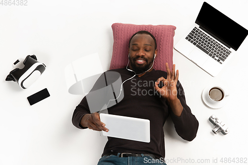 Image of Emotional african-ameican man using gadgets isolated on white studio background, technologies connecting people. Online shopping, showing nice