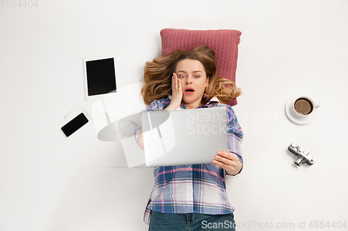 Image of Emotional caucasian woman using gadgets isolated on white studio background, technologies connecting people. Crazy shocked
