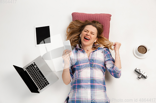 Image of Emotional caucasian woman using gadgets isolated on white studio background, technologies connecting people. Betting, winner